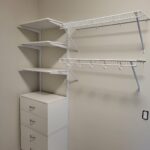 Closet shelving system with painted cabinet base, three shelves, and wire hanging rods installed.