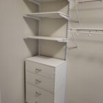 Painted face-frame closet shelving unit with four drawers and three open shelves installed in closet.