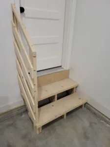 Garage stair with two open treads (three risers) up to a house door, slat rail on the open side