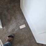 Painted white baseboard installed along apartment hallway wall above carpet flooring.