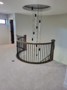 Completed curved railing with iron balusters, dark wood handrail and newel posts around a loft opening.