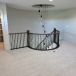 Completed horizontal-rod railing with dark wood newel posts and metal balusters around curved loft opening.