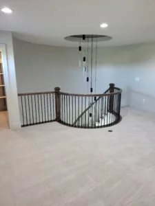 Completed railing with black metal balusters and dark wood newel posts around a curved loft opening.
