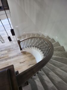 Curved staircase with installed wood balusters and handrail, painted finish complete.