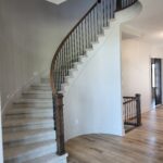 Curved staircase with painted risers, horizontal metal balusters, and dark wood newels—complete railing system.