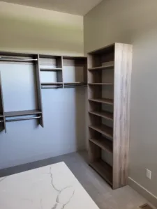 Walk-in closet with multiple shelves and hanging rods, wood-tone finish