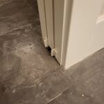 Painted door casing and jamb with door stops installed at floor level, meeting tile flooring.
