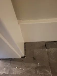 Painted white baseboard installed at a wall-to-floor transition meeting tile flooring