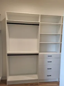 Painted face-frame closet system with hanging rods, open shelves, and a drawer tower installed