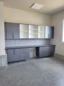 Installed garage cabinetry with upper and lower boxes, open shelving, and a slatwall backsplash