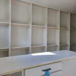 Custom built-in closet shelving with face-frame construction, multiple shelves, hanging rods, and countertop work surface—fully painted and finished.