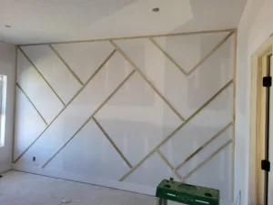 Chevron pattern accent wall with raw wood strips over drywall, unfinished and not yet painted