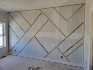 Chevron pattern accent wall with raw wood strips over drywall, unfinished and unpainted