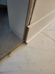 Wood-tone trim at a door threshold meeting tile flooring nearby