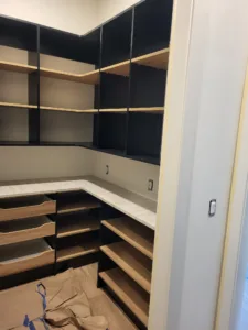 Built-in closet cabinetry with black frame, open shelving, wood drawers, and countertop installed