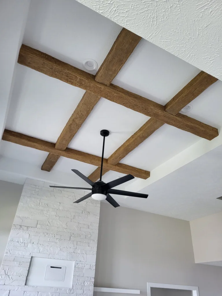 Exposed wooden beams and modern ceiling fan in a stylish interior.