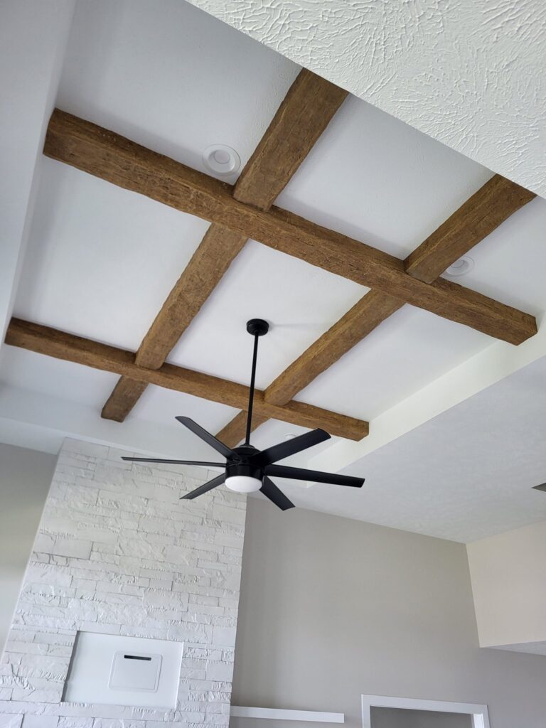Exposed wooden beams and modern ceiling fan in a stylish interior.
