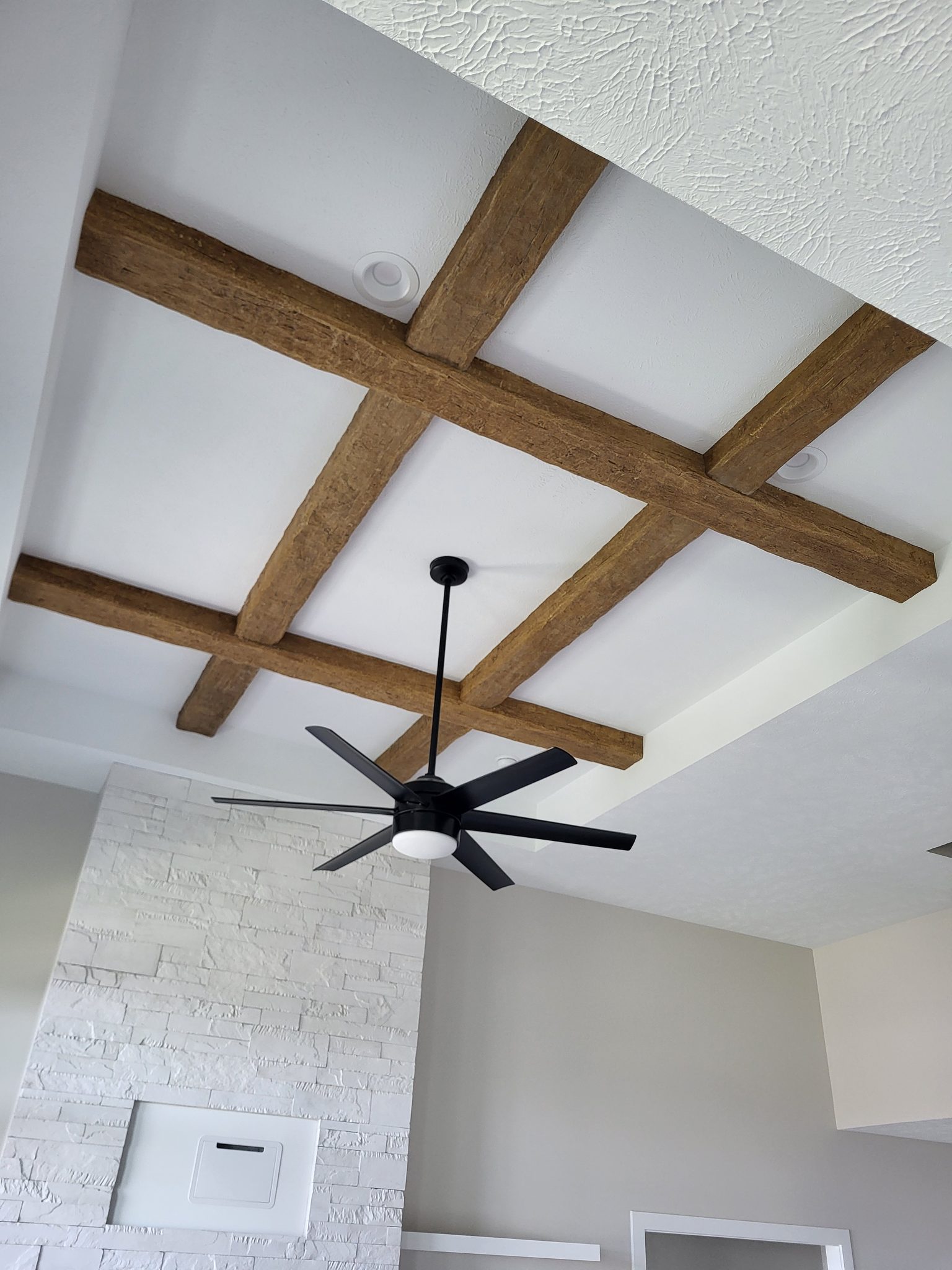 Exposed wooden beams and modern ceiling fan in a stylish interior.