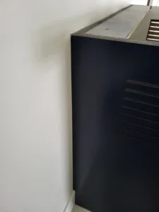 Dark cabinet door with horizontal slat design and gray countertop edge, mounted on wall
