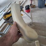 A worker is holding a piece of wood nosing, which is being prepared for installation on the stairs. The photo captures the ongoing work process.