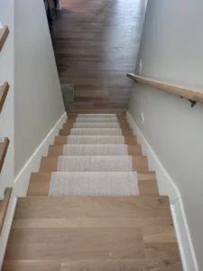 Finished interior staircase with carpet treads, wood nosing, and a wall mounted handrail