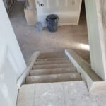 Staircase skirt boards installed on both sides with open treads, mid-construction phase.