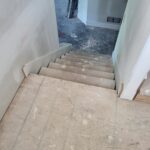 Finished stair risers installed with white skirt boards, raw wood treads ready for paint.
