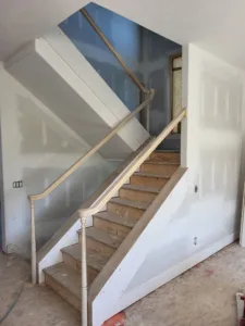 Turned wood newel post and handrail on a staircase with painted white stringers and wood treads
