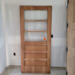 Finished wood interior door slab with glass and panel design, ready for installation.