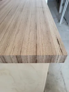 Butcher block countertop edge showing laminated wood grain, mounted on a plain wood cabinet