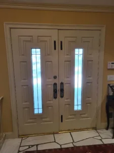 Painted cream double entry doors with narrow glass insert, decorative hardware and casing, completed