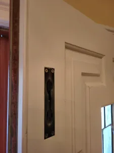 Dark metal flush edge pull mounted on a painted door, installation complete