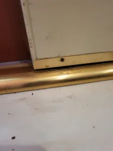 Brass threshold strip installed at a door opening, floor level detail visible