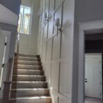 Finished staircase with painted skirt boards, wall-mount handrail brackets, carpet treads, and completed interior trim and doors.