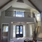 Horizontal-rod railing on mezzanine level with dark wood newel posts and metal rod balusters in completed foyer.