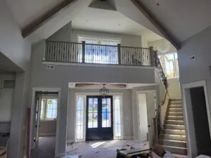 Second-floor mezzanine railing with dark wood cap and posts, black metal balusters, foyer below.