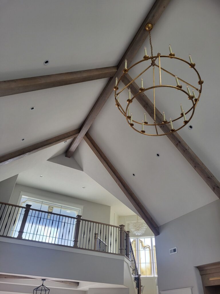 Interior view of a modern home with exposed beams and a chandelier.
