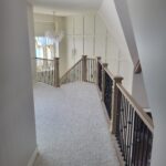 Completed iron baluster railing with dark wood newel posts and handrail, installed on upper hallway landing.