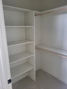 Finished walk in closet with painted shelving units and a hanging rod on one wall