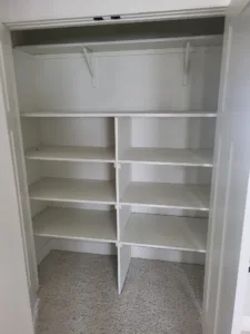 Finished white closet shelving with multiple tiers and center divider, no doors or rod visible
