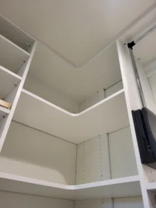 Painted white closet corner shelving with diagonal support brackets and a rod bracket installed