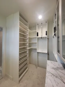 Finished closet with diagonal shoe shelving, hanging rod, and cabinet drawers under a marble top