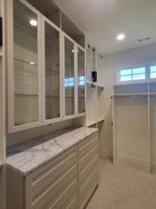 Built-in closet cabinet with glass-front upper doors, marble-look countertop, and drawers below