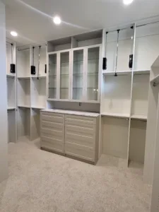 Finished closet cabinetry with glass front upper doors, drawer base, and open shelving installed