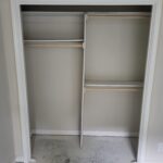 Closet opening with white casing and interior shelving/rod frame installed, ready for bi-fold door slabs.