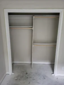 Painted closet casing with a shelf and double hang rods installed, no doors hung yet.