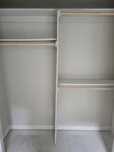 Closet shelving with painted white shelf and hanging rod on adjoining walls, empty closet corner.
