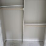Closet shelving and hanging rod installed with white-painted frame and raw wood shelves, ready for paint.