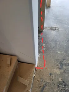 Exterior door jamb with layout marks on the concrete floor for threshold and sill positioning