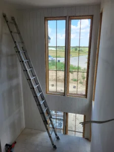 Tall windows cased with wood trim on a shiplap wall, casing reaching well above head height